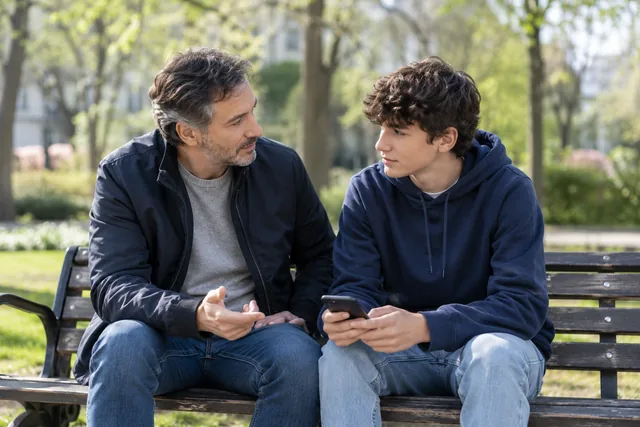 Um pai e um adolescente conversando em um parque — fotografia gerada por IA
